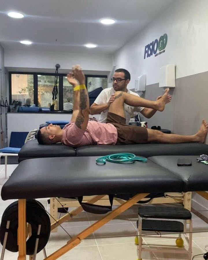 Fisioterapeuta da FisioGo atendendo paciente na maca, com a parede do logo ao fundo